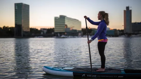 girl on sup board, city view